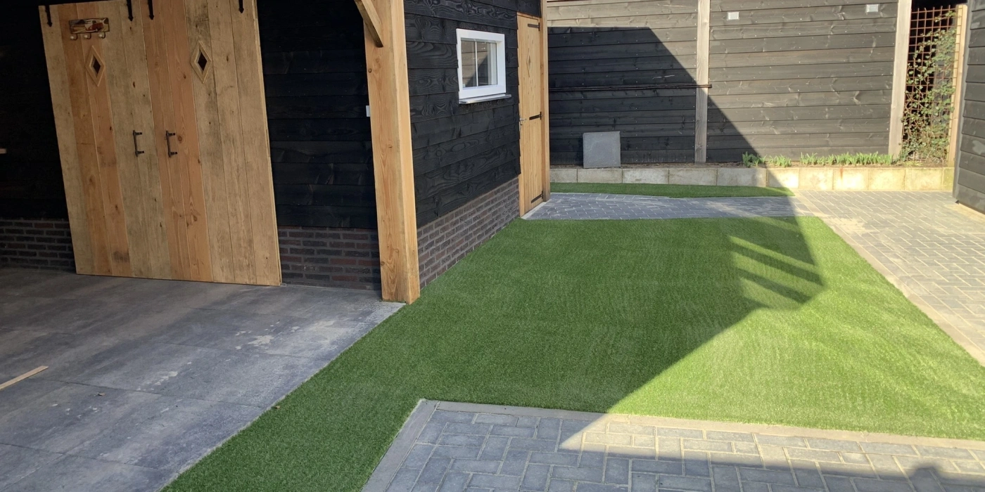 Strakke en groene achtertuin met kunstgras in Steenwijk